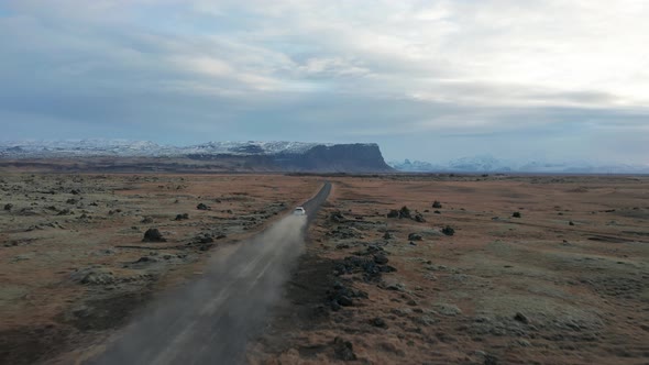 4K drone video of car driving away on a dirt road in Iceland. alt