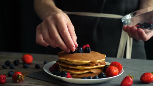 Female Hands Decorating Pancakes By Berries