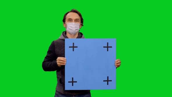 Man In Protective Mask Looking At Camera And Holding Blank Board