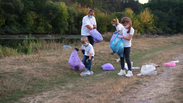 A family of volunteers with children clears the river Bank of garbage.