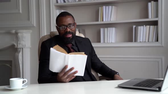 African-American Bearded Man in a Black Suit, Shirt, Stylish Glasses. A Businessman Is Working on a alt