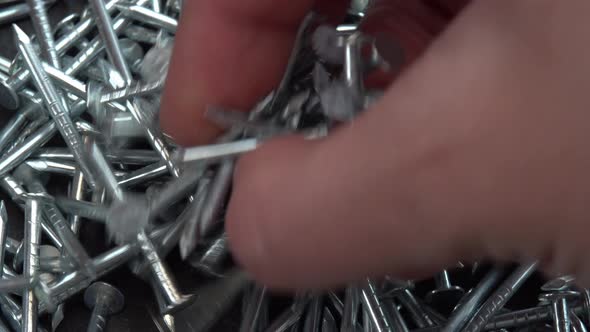 Hand Takes Metal Nails for Construction Work Hobnails are Spinning Close Up Background Pin or Spike alt