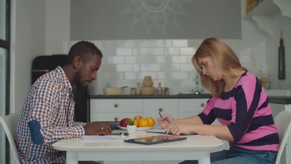 Diverse Couple Managing Family Budget in Kitchen alt