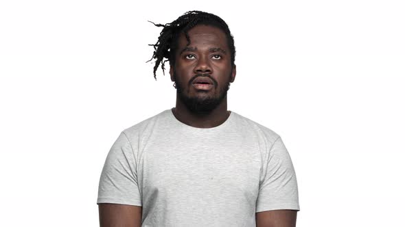 Portrait of Disinterested Displeased Dark Skinned Guy in Casual Tshirt with Afro Pigtails Rolling alt