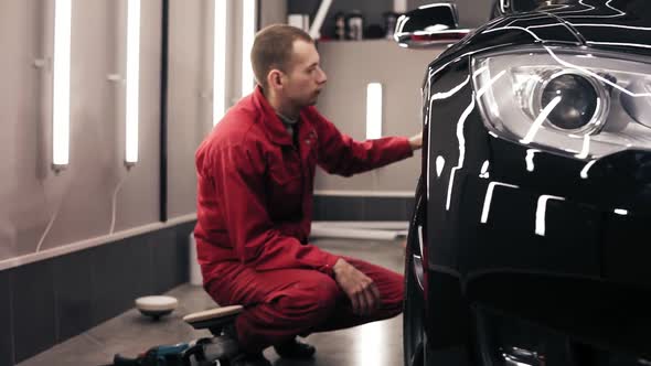 Autocenter Worker Doing the Final Wiping of Perfectly Polished New Black Car alt