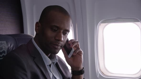 Businessman talking on cell phone on airplane flight