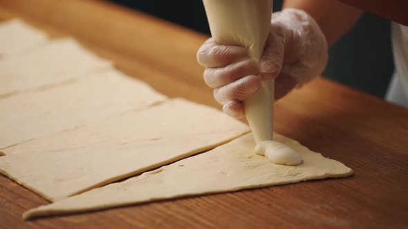 Woman making a croissant from dough in the kitchen alt