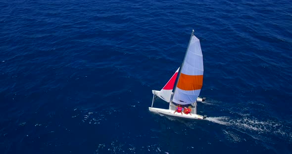 Aerial drone view of a man and woman sailing on a boat to a tropical island alt
