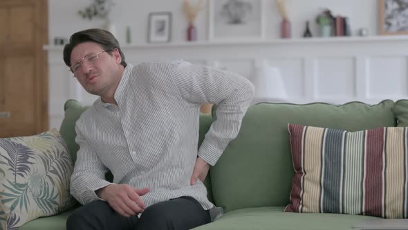 Young Man having Back Pain on Sofa alt