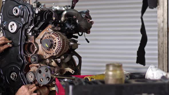 Car Mechanic Adjusts Front Housing Of Car Engine In Repair Shop alt