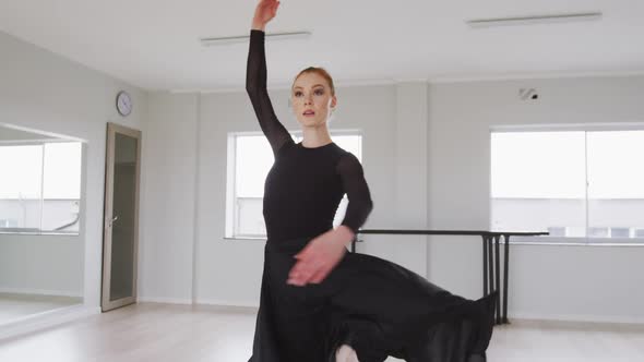 Caucasian female ballet dancer practicing ballet during a dance class in a bright studio alt