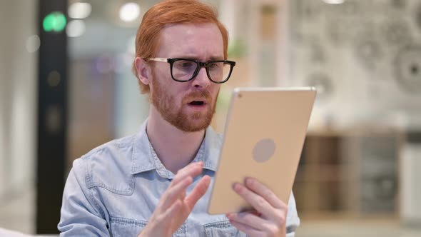 Portrait of Upset Casual Redhead Man Reacting To Loss on Tablet  alt