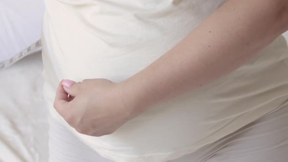 pregnant woman sitting on bed measuring big belly female advanced pregnancy last trimester