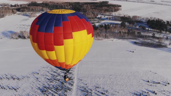 People Fly on a Big Bright Balloon Over the Winter Forest