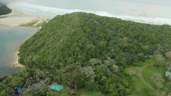 Aerial tilt up over house with a pool and volleyball court near ocean alt