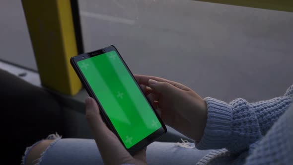 Woman's Hand Holding a Smartphone with a Green Screen in Tram. Chroma Key