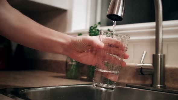 Man Filling a Glass of Water Before to go to Bed