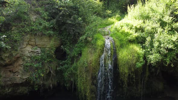 aerial view of a beautiful waterfall with blue lake in the forest.