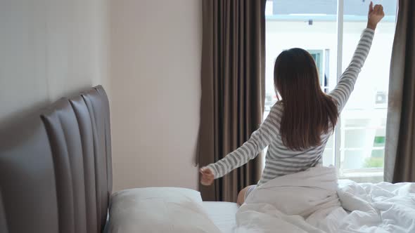 Young asian woman sitting on the bed and stretch oneself in the morning