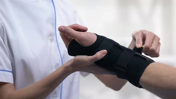 Female Therapist Applying Titan Wrist Brace to Male Patient, Trauma Treatment alt