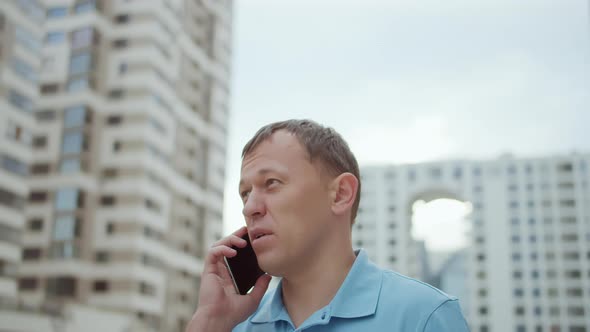 Attractive Young Man Talking on the Phone Standing on the City Street alt