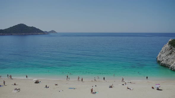 People Enjoy Relaxing on Beach with Soft Sand on Sunny Day alt