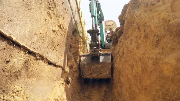 In the Trench, the Excavator Lifts the Earth
