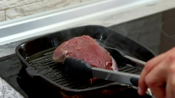 Chef Turns Large Piece of Fresh Juicy Beef Steak with Tongs on Grill Pan