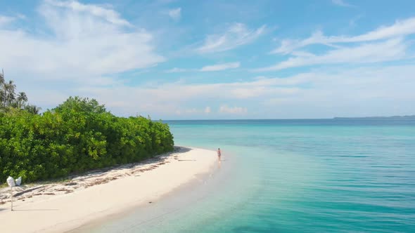 Aerial slow motion: lady walking on tropical beach at sunset, away from it all alt
