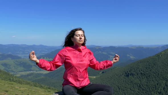 The girl sits on the top of the mountain and meditates. Relax in nature. Happiness and tranquility