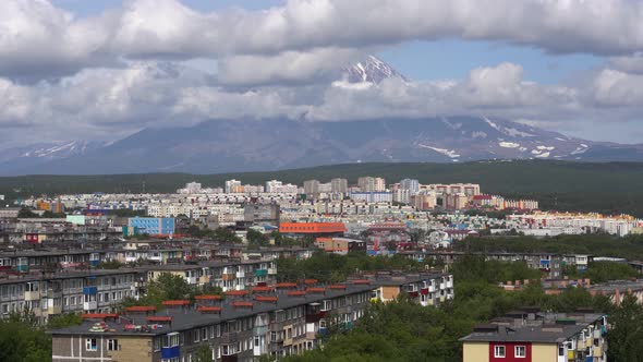 Sunny Summer Cityscape on Background of Volcano Clouds Floating Across Sky