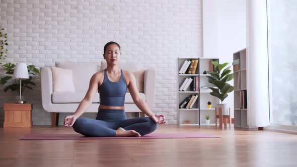 Asian woman practice yoga lotus pose to meditation at home. alt