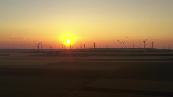 Eolian turbine farm at sunrise. Wind turbine silhouette. Wind field turbines alt