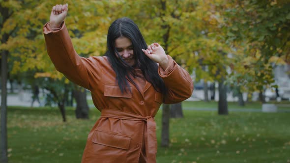 Attractive Energetic Happy Young Woman Actively Dancing Incendiary Moving Outdoors in Autumn Park alt