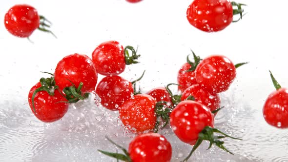 Super Slow Motion Shot of Cherry Tomatoes Flying Into Water on White Background at 1000Fps alt
