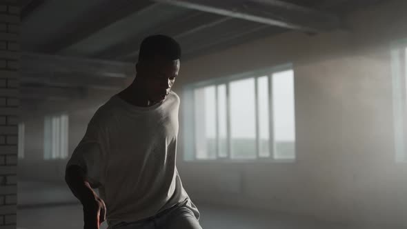 A Black Man Makes a Football Freestyle with a Ball in an Underground Parking Lot in the Sunlight alt