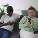 Happy Biracial Couple Relaxing on Sofa with Smartphones - VideoHive Item for Sale