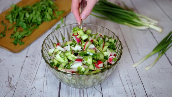 Hands Chef Stirring with a Spoon a Vegetable Salad with Radish Cucumber Greens alt