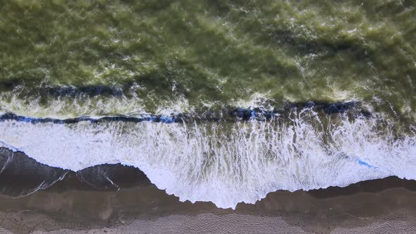 Top view of Sea green waves hitting the shore on a sandy beach alt