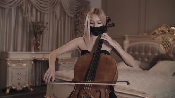 beautiful girl in mask playing the cello in a beautiful room. repetition . close-up. Pandemic. Covid