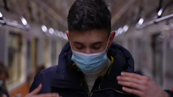 Young Man Putting on Protective Mask in Metro alt