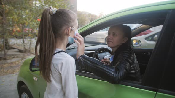 A Woman Puts a Medical Mask on Her Daughter's Face and Sends Her to School alt