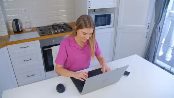 Young adult blond girl working on laptop computer keyboard in 4k stock footage alt
