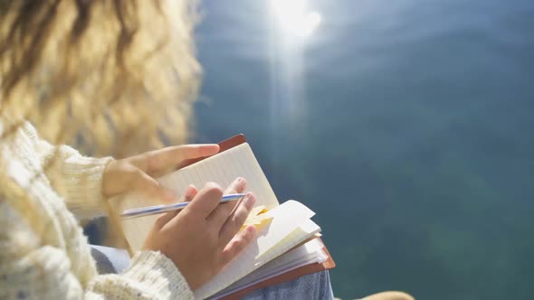 Woman Hipster Writes in Diary Sitting on Beach