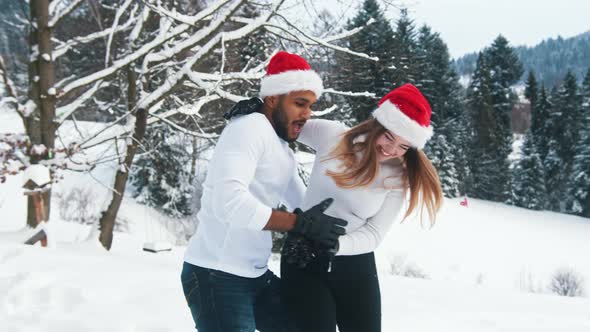 Happy Young Couple Having Fun on the Snow with Christmas Hats alt