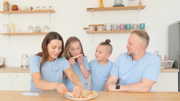 Young Family Deliciously Eating Italian Pizza Sitting in the Kitchen at the Table alt