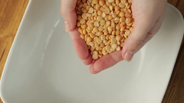 Closeup of a Woman's Hands Pouring Whole Grains of Dried Peas Into a Plate alt