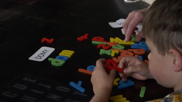 Mom teaches her son how to say the words on the cards and letters at home at the table