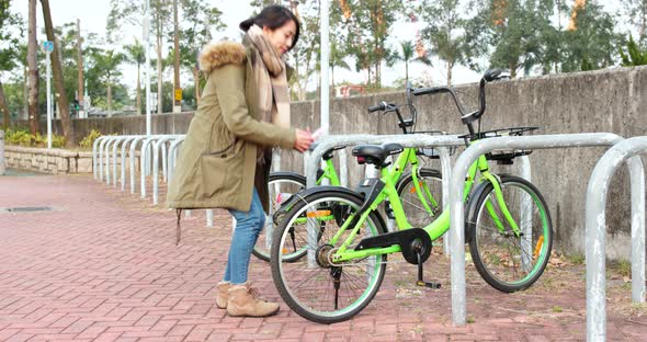 Woman using share bike in city alt