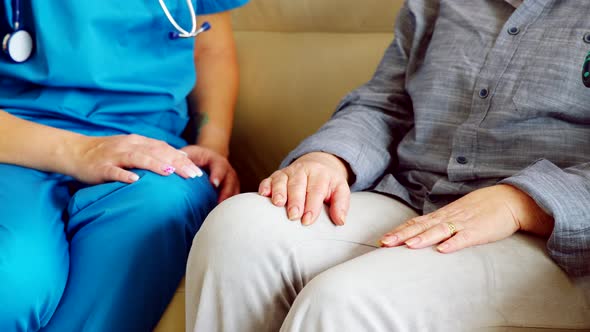 Close Up of Female Nurse Holding Senior Woman Hand alt